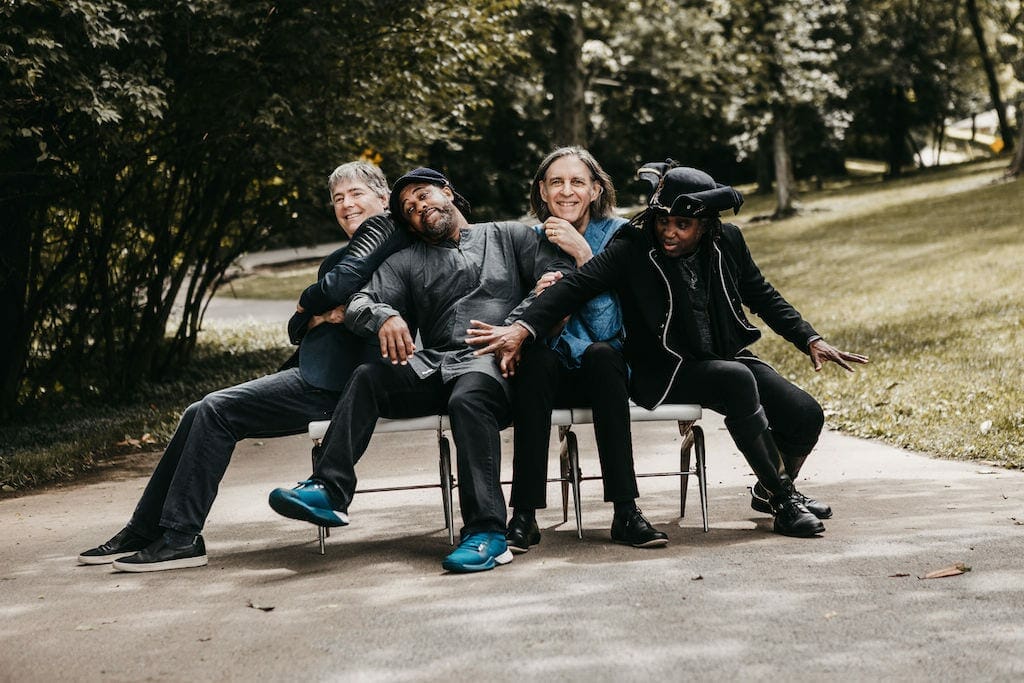 Bela Fleck and the Flecktones pose outdoors.