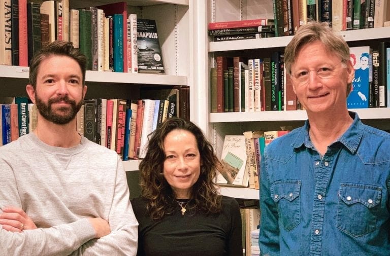Three people in front of a case of books at Sweet Melissa Records and Books