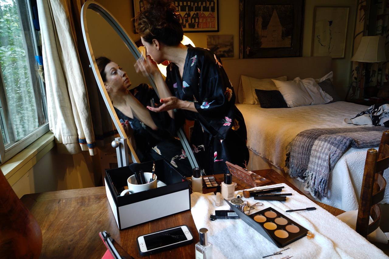 A photo of actress Park Krausen putting on make up in front of a mirror.